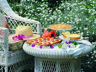 photo of varieties of desserts on wicker table beside yellow straw hat on wicker chair