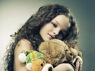 girl holding brown bear plush toy