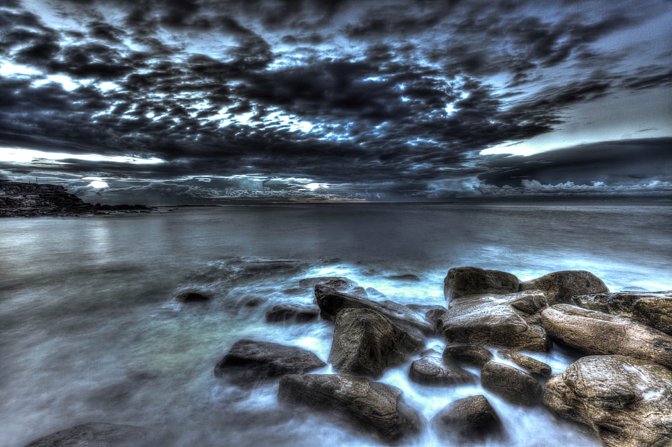 landscape photography of rocks on seawater under cloudy sky during daytime HD wallpaper