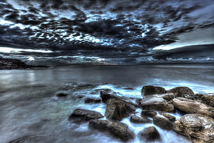 landscape photography of rocks on seawater under cloudy sky during daytime