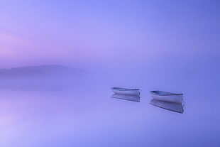 two canoe on misty body of water near island