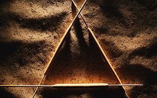 three rods forming a triangle on brown sand