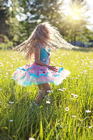 girl swaying her hair and floral dress in the middle of daisy flower garden