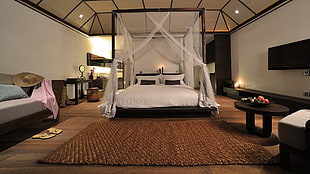 brown wooden canopy bed with white mesh curtain