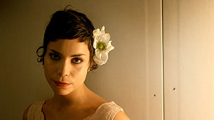 photo of woman with with Magnolia flower on her left ear wearing white sleeveless top