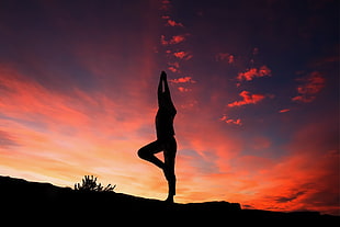 silhouette of human doing yoga during golden hour photo