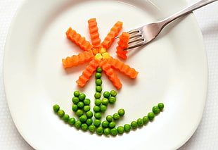 green peas and carrots on white ceramic plate with aluminum fork