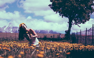 woman in bed of flowers near fence during daytime