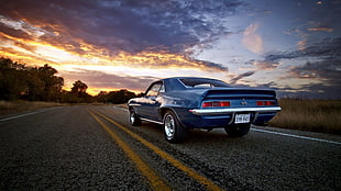classic blue Ford Mustang on open road during golden hour