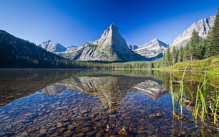 reflection of mountain on clear water under blue sky during daytime HD wallpaper