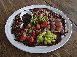strawberry, grapes and kiwi fruits on top of white plate covered in chocolate