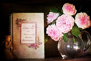 white spiral book beside pink flowers