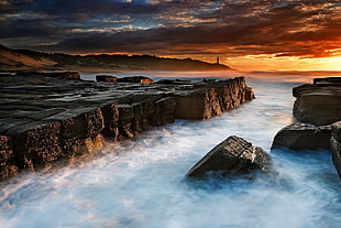 brown and white boat on body of water, sunset, cliff, sea, clouds