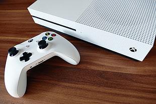white Xbox One with game pad on brown wooden table top