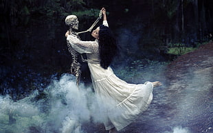 woman dancing with skeleton between forest trees HD wallpaper