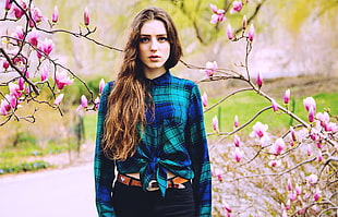 woman in blue and teal long-sleeve shirt with black bottoms and brown leather belt with pink Magnolia Blossom tree