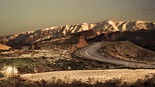photo of desert dunes with road and mountains during day time