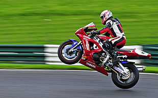 man driving red and black Yamaha sports motor cycle