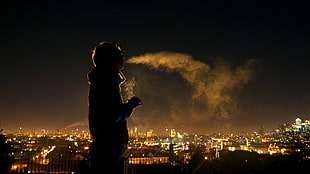 silhouette of person smoking in front of buildings