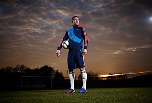 male soccer athlete wearing blue jersey standing during golden hour