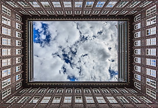 low-angle photography of brown high-rise building under white clouds