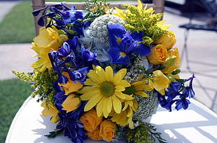 shallow focus photography of yellow and blue flower arrangement on white table under sunny sky