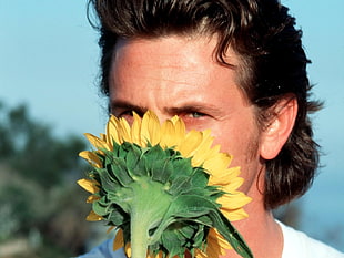 selective focus photography of man holding sunflower