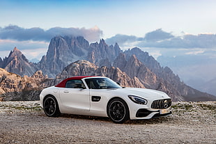 white Mercedes-Benz sports coupe soft top on dirt road near mountain at daytime