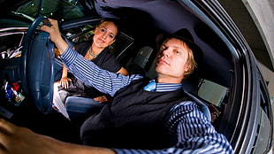 man in black vest sitting inside the car beside woman