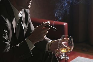 man sitting while holding clear wine glass and tobacco HD wallpaper