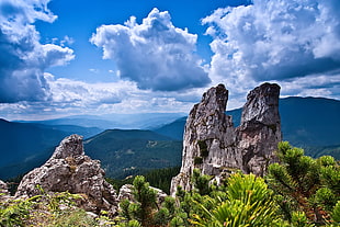 landscape photo of rocks with background of forest covered mountains