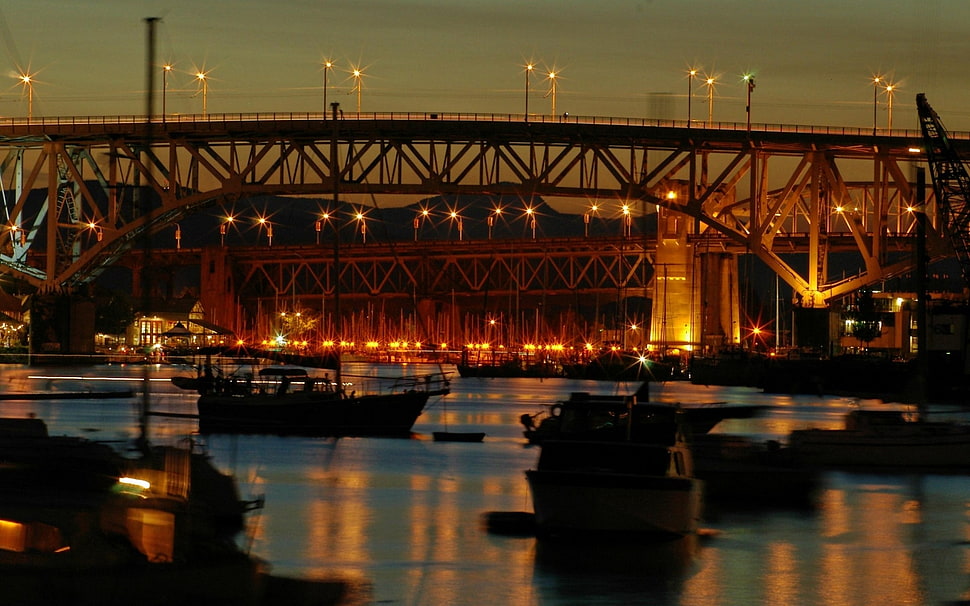 boats under a suspension bridge at night HD wallpaper