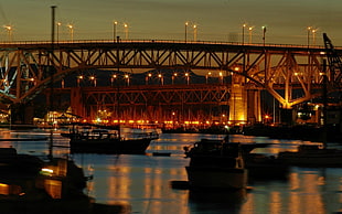 boats under a suspension bridge at night