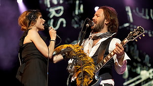 women's wearing sleeveless dress holding a microphone in front of a man