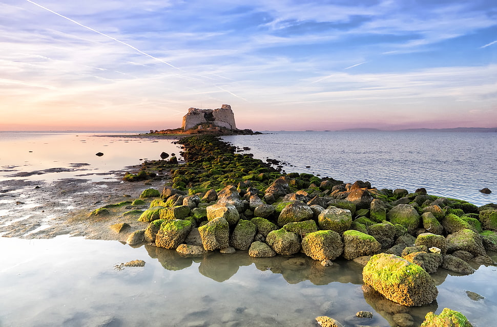 island with stones under blue sky HD wallpaper