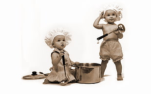 two children wearing white hat holding stainless steel ladles