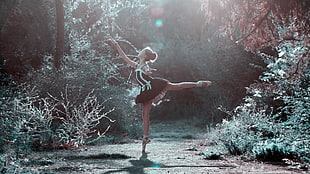 ballerina in black dress dancing in forest