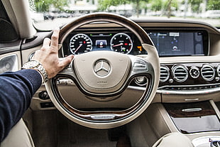 person taking photo of grey Mercedes-Benz steering wheel
