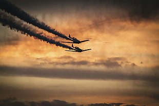 two gray aircrafts flying during sunset
