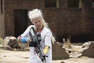 woman holding a gun wearing white short-sleeved top during daytime