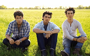 three men sitting on grass photo