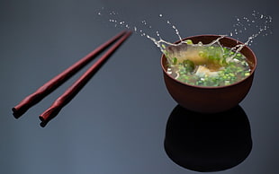 noodle soup in brown bowl beside set of chopsticks