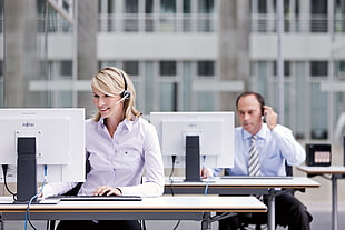 woman and man sitting near computer desk wearing dress shirts