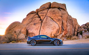 black sports coupe on asphalt road near brown rock formation during daytime
