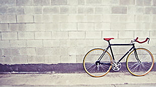 black road bike parked near gray concrete wall