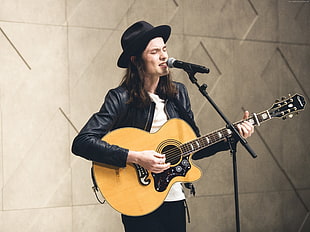 man in black leather jacket paying guitar while singing