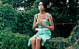 woman in green sleeveless dress sitting beside plants