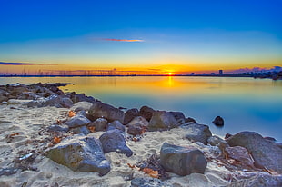 landscape photography of gray rocks beside body of water during golden hour HD wallpaper