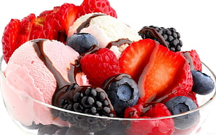 strawberry ice cream with black berries in clear glass bowl