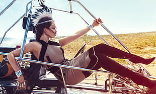 woman in gray see through halter top dress with black boots riding in dune buggy posing for photo during daytime